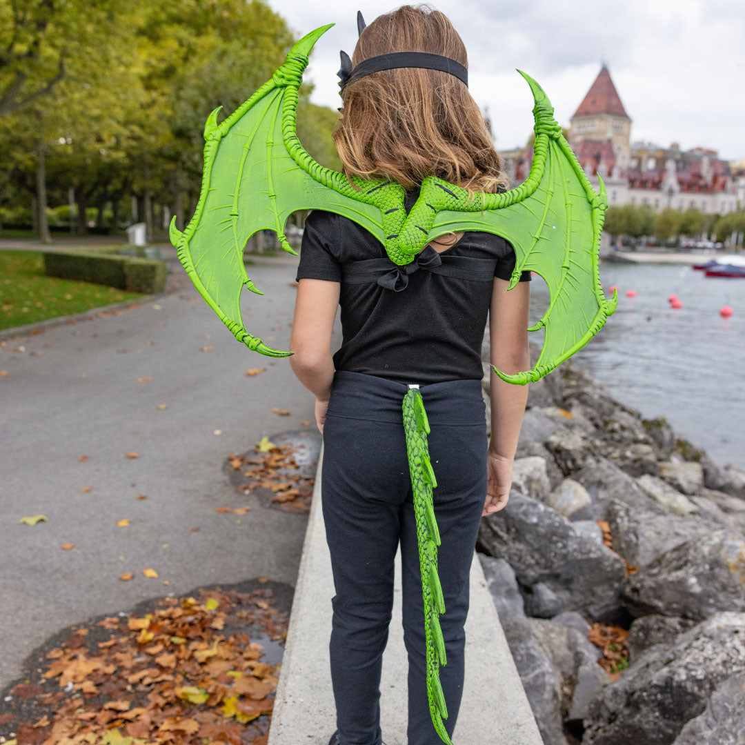 Kind van achteren gezien met Great Pretenders groene drakenvleugels en staart bij een meer.