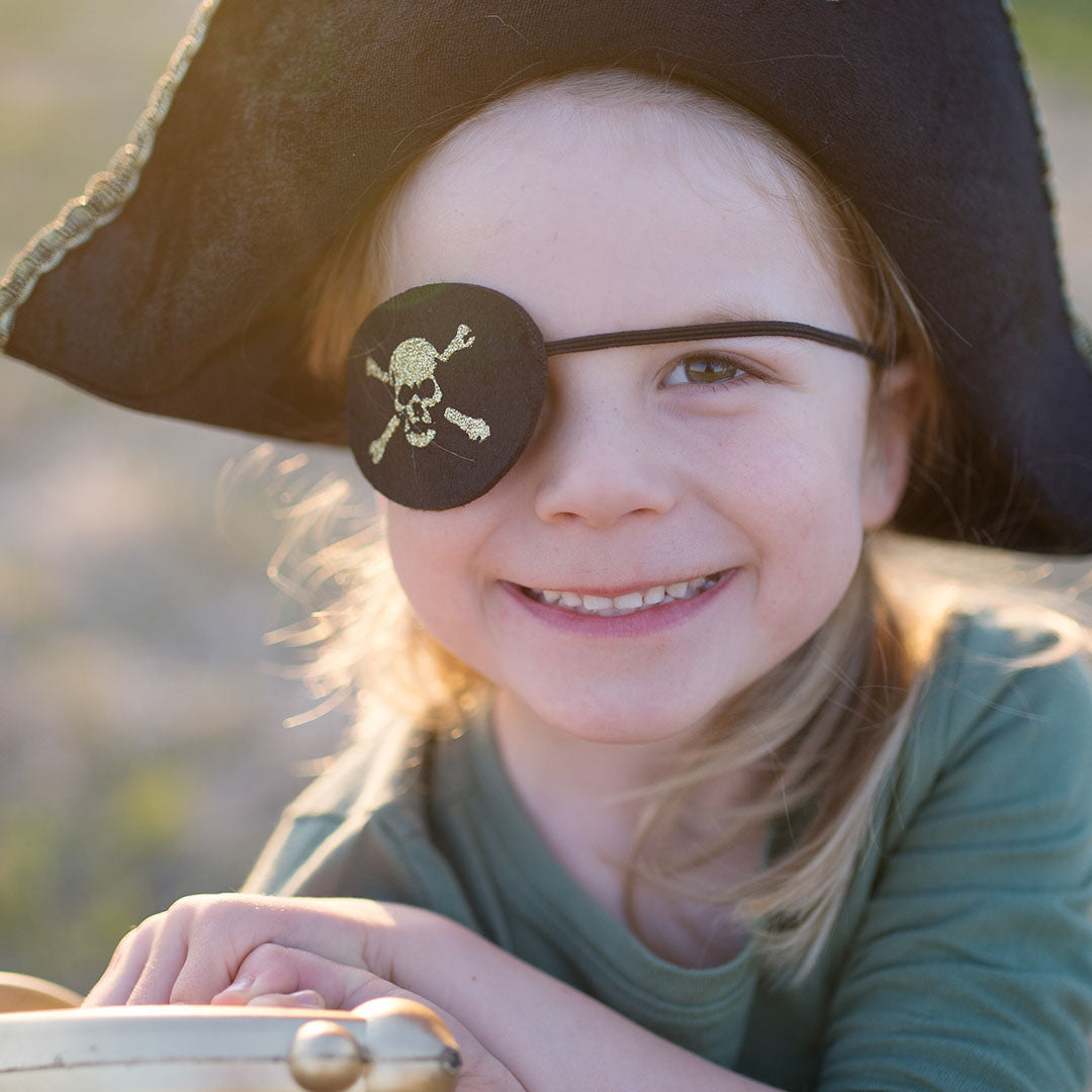 Close-up van een lachend kind met Great Pretenders piraten ooglapje en hoed.