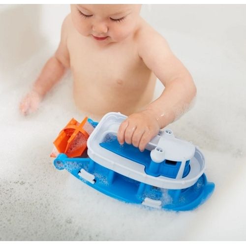 Een baby speelt met de blauw-witte badspeelgoed boot in een schuimend bad.