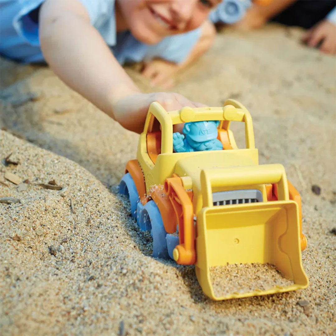 Een kind speelt met de Green Toys oranje shovel in het zand.