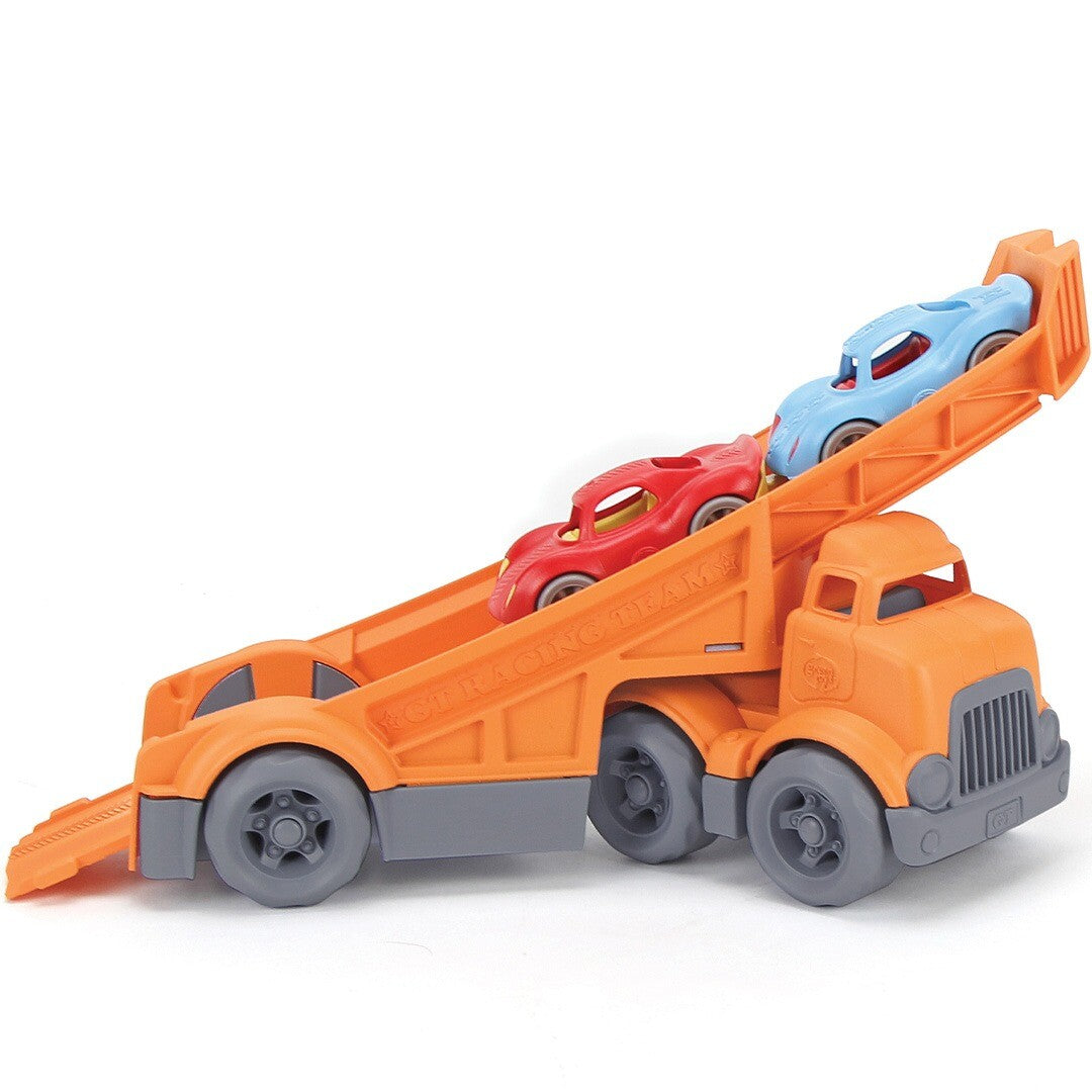 Green Toys speelgoedvrachtauto van de zijkant, met de laadklep schuin omhoog en twee racewagens erop.