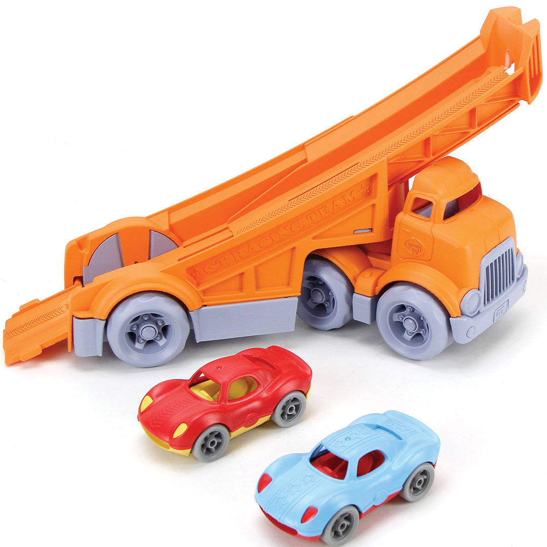 Green Toys speelgoedvrachtauto met de laadklep omhoog, en de rode en blauwe racewagens liggen ervoor.