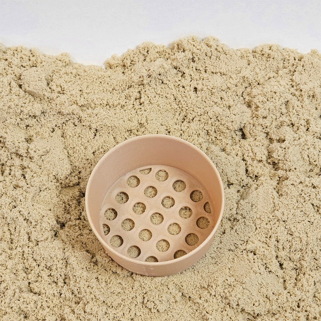 De grennn mini zeef ligt in een berg kinetisch zand.
