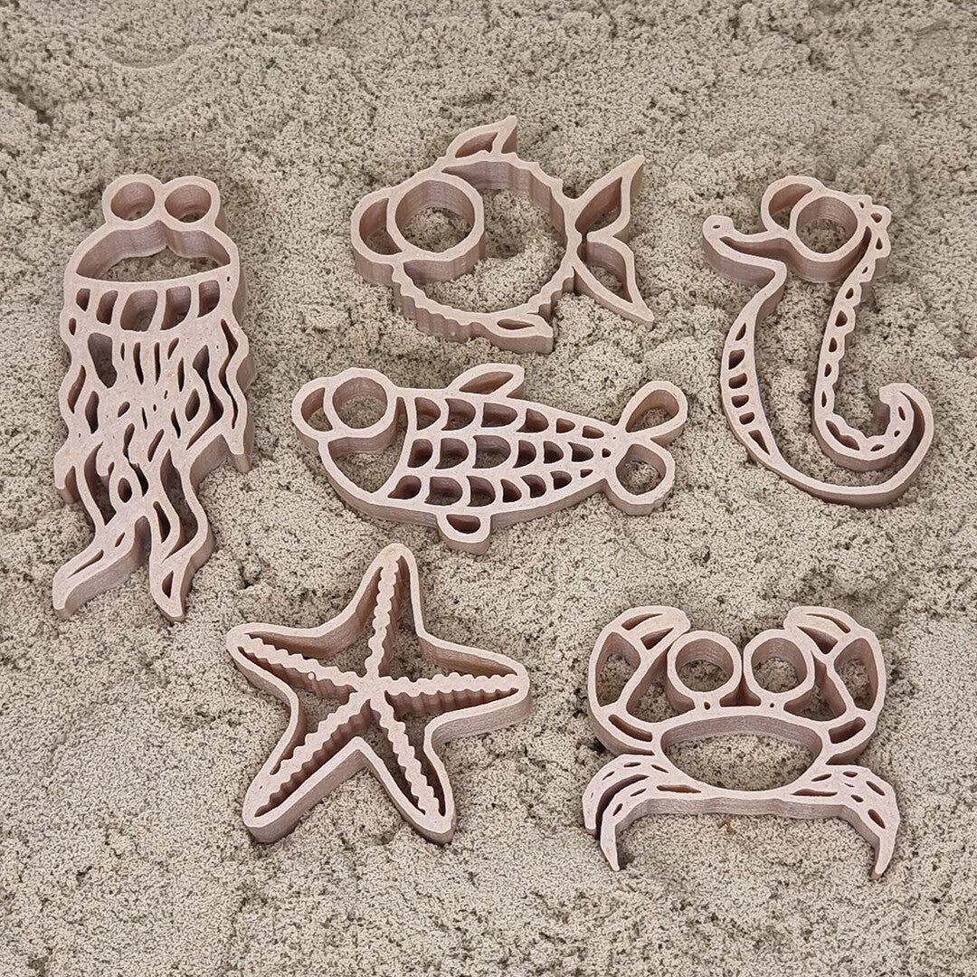grennn zandbak uitsteekvormen van zes zeedieren deels in het zand.