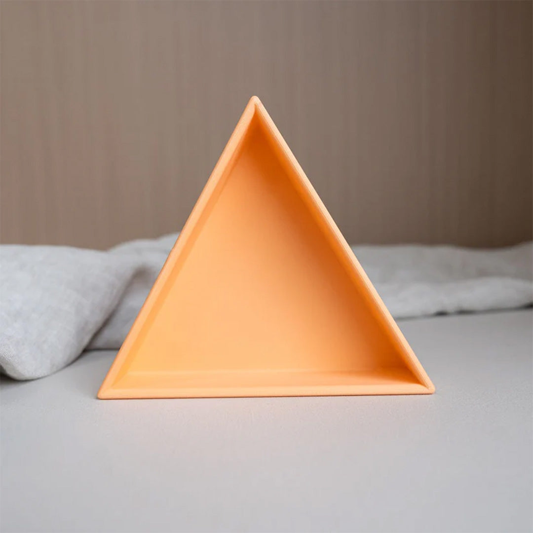 grennn pastel oranje driehoekig inlegbakje van plastic op een grijze ondergrond.