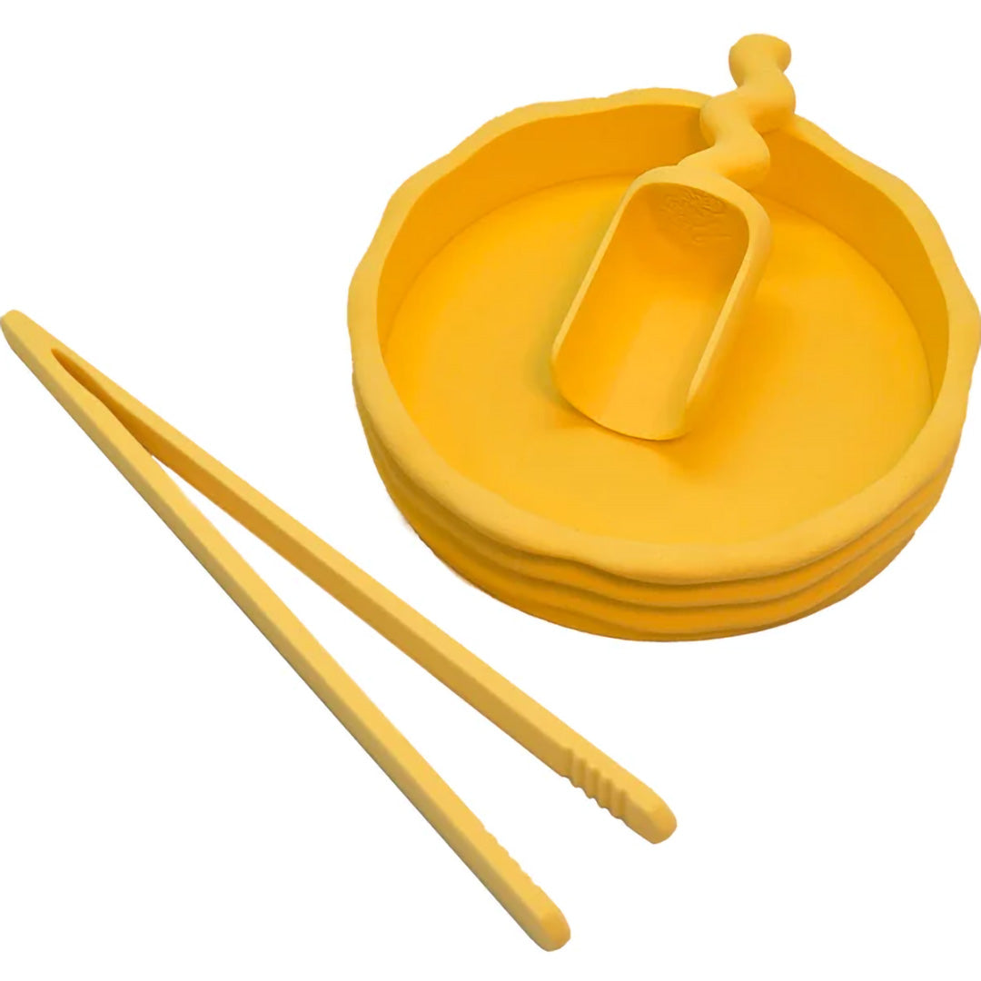 Een geel grennn pincet naast een gele ronde kom en een gele schep voor sensorisch speelgoed.