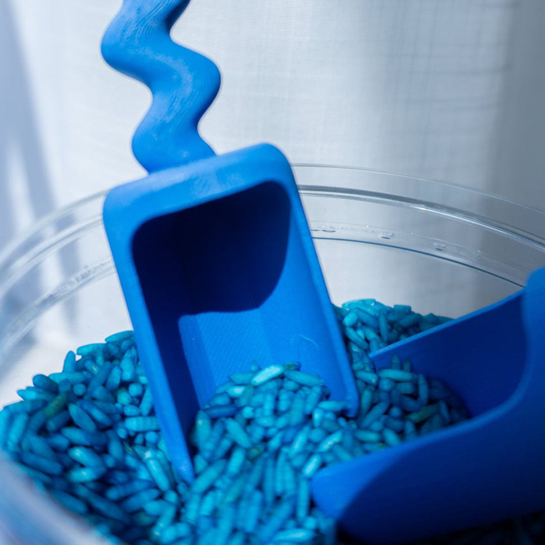 Twee blauwe schepjes in een bak met blauwe speelrijst.