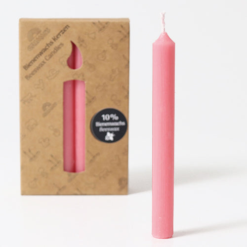 Grimm's roze bijenwaskaarsje naast de bruine verpakking met uitgesneden kaarsvorm.
