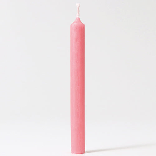 Een enkel roze bijenwaskaarsje staat rechtop.
