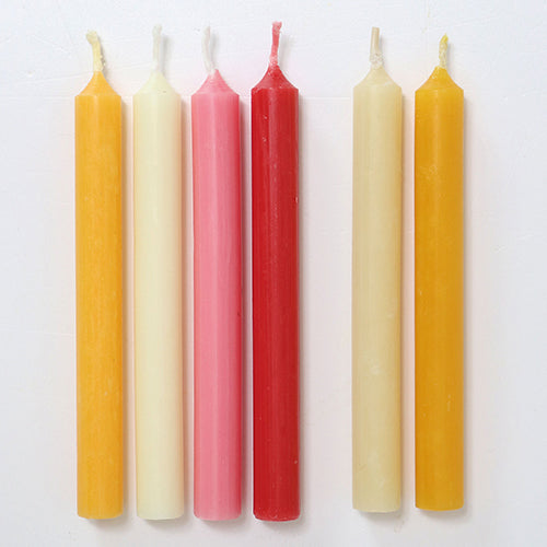 Zes bijenwaskaarsjes in verschillende kleuren: geel, crème, roze en rood.