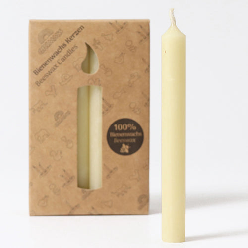 Grimm's crème bijenwaskaarsje naast de bruine verpakking met kaarsvormige uitsparing.