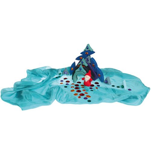 Een gestileerde boom van houten blokken op een blauwe doek, versierd met grimm's kleurrijke acryl diamanten en een kabouterfiguur.