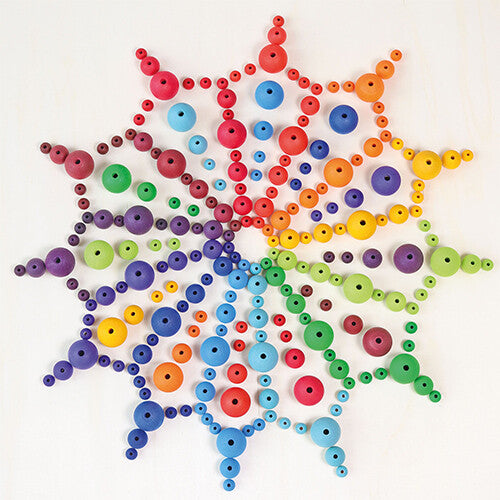 Een mandala-patroon gemaakt van grimm's houten kralen in diverse maten en regenboogkleuren.