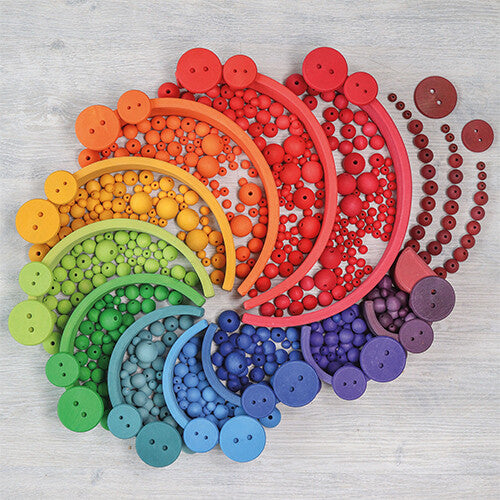 grimm's houten kralen en knopen in regenboogkleuren, gerangschikt in concentrische bogen.