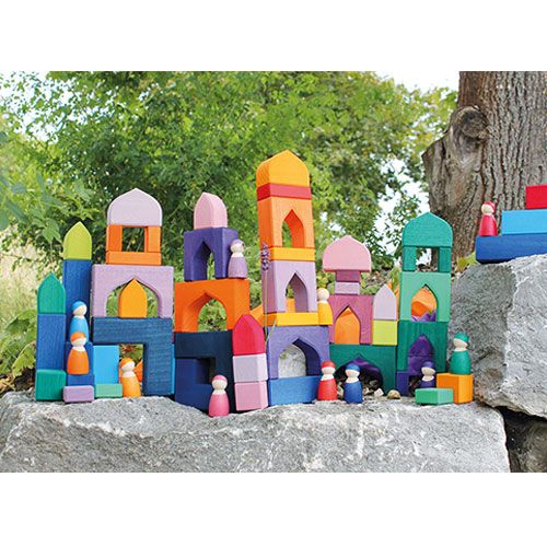 Grimm's houten bouwblokken 1001 nacht vormen een kleurrijk kasteel met poppetjes op een rots in de natuur.