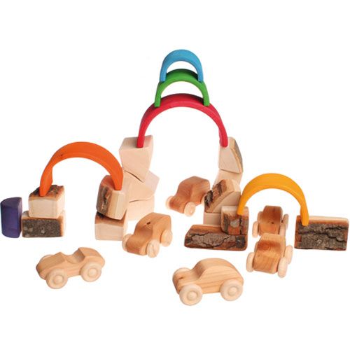 Een speelscène met grimm's houten bouwblokken met boomschors, houten autootjes en gekleurde houten bogen.