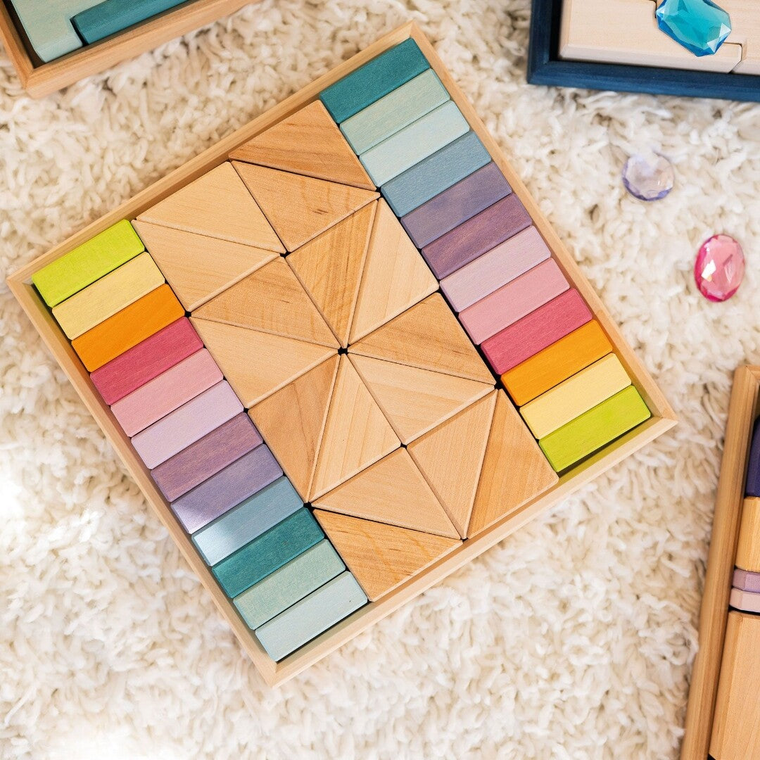 grimm's houten bouwblokken pastel duo in de houten kist, liggend op een witte pluizige ondergrond.