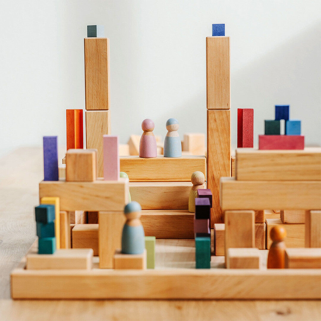 Een stad van Grimm's houten bouwblokken met gekleurde accenten en houten poppetjes.