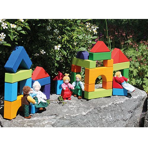 Grimm's kleurrijke houten bouwblokken vormen kleine huisjes waar poppen mee spelen, buiten op een rots.