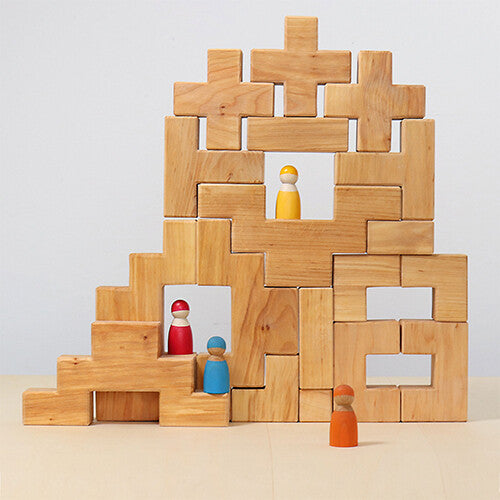 Een kasteelachtige structuur gebouwd van Grimm's natuurlijke houten bouwblokken met gekleurde houten poppetjes erin.