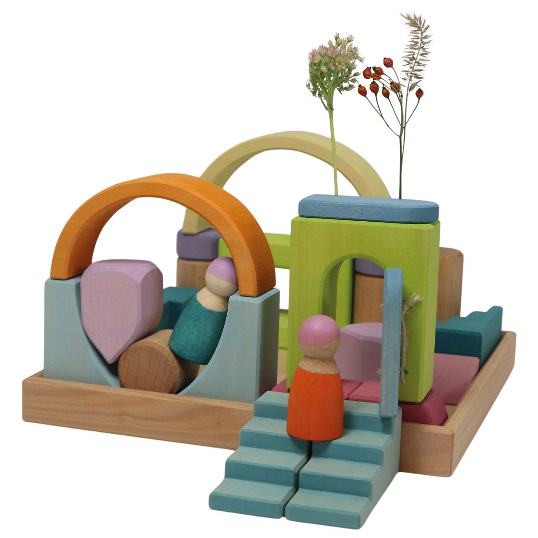 Grimm's houten bouwblokken wolkenspel, opgebouwd als een fantasievol landschap met twee poppetjes en gedroogde bloemen.