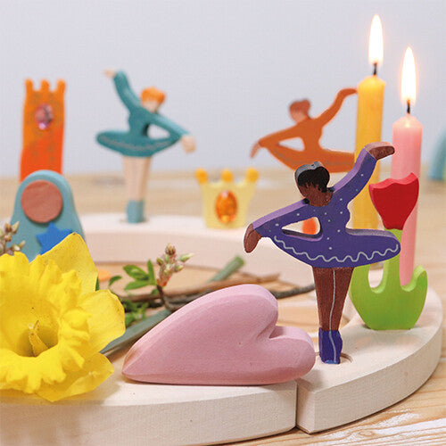 De paarse Grimm's ballerina decoratie figuur staat in een ronde houten kaarsenhouder met andere figuren, kaarsen en een gele bloem.