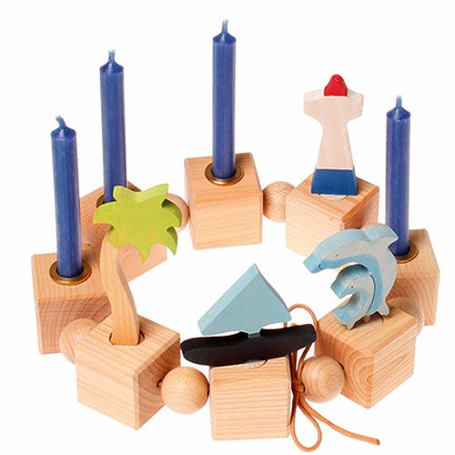 Grimm's houten decoratie figuren in een cirkel, waaronder een palmboom, vuurtoren, boot en dolfijntjes, met blauwe kaarsen.