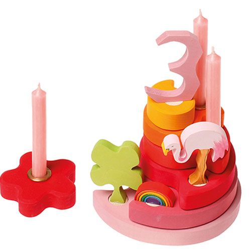 Grimm's houten decoratiefiguur van een groen klavertjevier, geplaatst in een roze houten verjaardagsring met kaarsen en andere figuren.