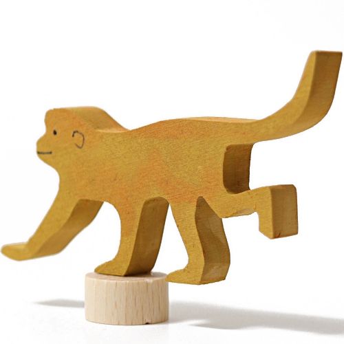 Grimm's houten decoratiefiguur van een gele lopende aap, van de zijkant gezien, balancerend op een houten voetstuk.