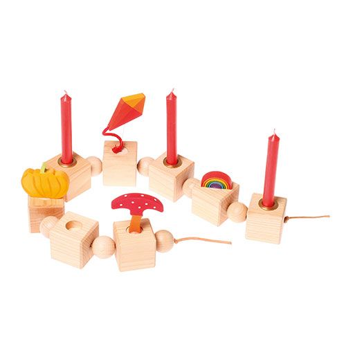 Een collectie Grimm's houten decoratiefiguren en rode kaarsen in een verjaardagsring.