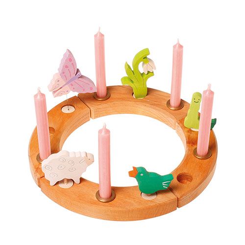 Houten decoratiering met roze kaarsen en diverse houten figuren, waaronder een schaap, vlinder en vogel.