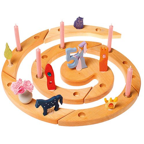 grimm's houten verjaardagsring met diverse decoratie figuren, waaronder de paarse uil, en roze kaarsen.