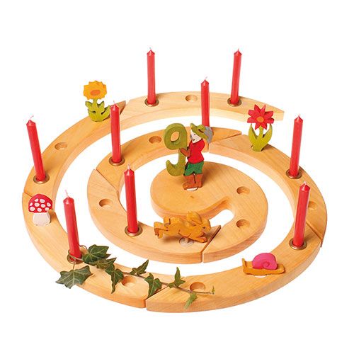 Een grimm's houten verjaardagsring met rode kaarsen en diverse natuurlijke decoratiefiguren, waaronder een vliegenzwam.