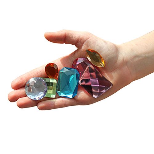 Een open hand toont de grootte van verschillende Grimm's glinster edelstenen.