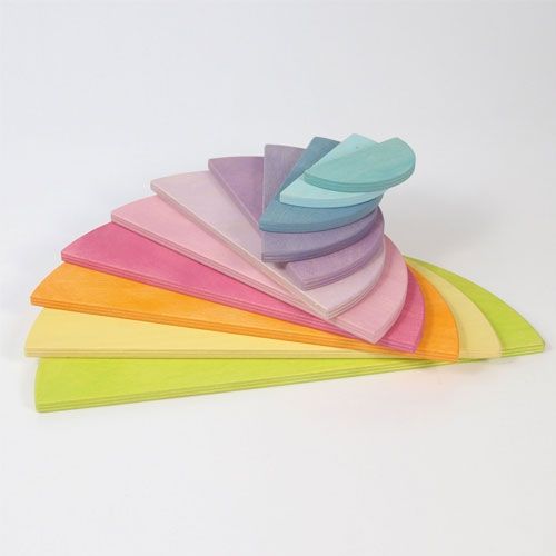 Grimm's pastel half-round houten bouwschijven gestapeld in een regenboogvorm met enkele losse schijven.