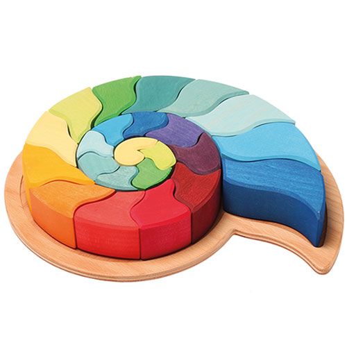 Grimm's houten ammoniet puzzel in regenboogkleuren, compleet in de houten basis, schuin van bovenaf.