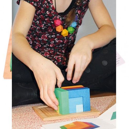 Een persoon bouwt de Grimm's veelkleurige houten puzzel tot een kubus.