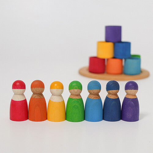grimm's houten regenboog vrienden staan op een rij, met de gekleurde kommen als piramide gestapeld op een houten schijf.