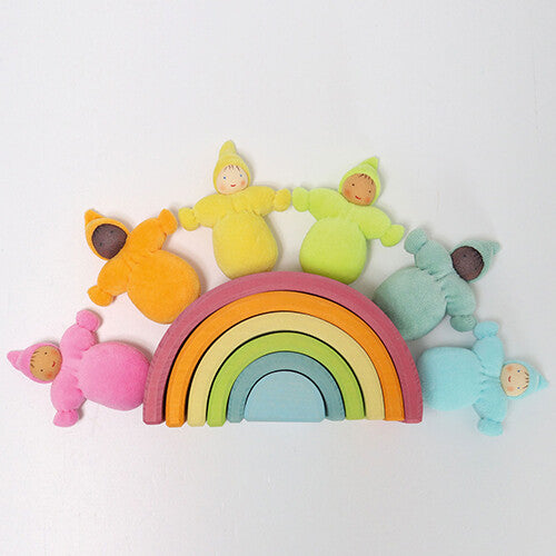 Zes grimm's kabouter poppen in pastelkleuren omringen een grote houten regenboog stapelaar.