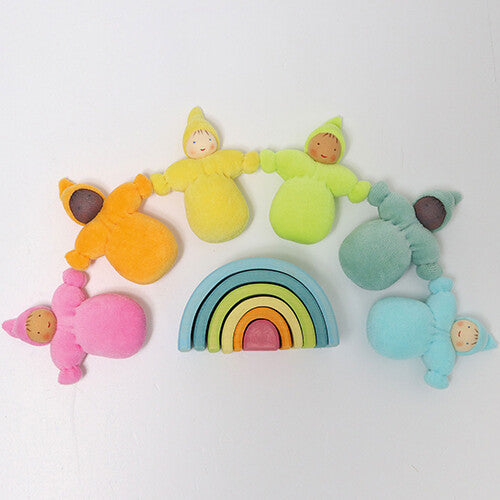 Zes grimm's kabouter poppen in pastelkleuren omringen een kleine houten regenboog stapelaar.