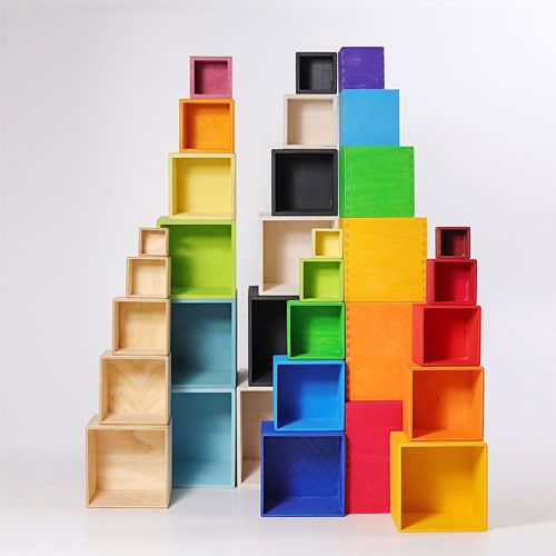Een grote verzameling Grimm's houten kubussen in diverse kleuren, gestapeld tot een kleurrijke muur.