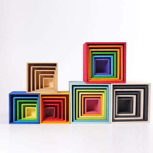 Meerdere sets Grimm's houten kubussen, waaronder een regenboogset, naast elkaar op een rij.