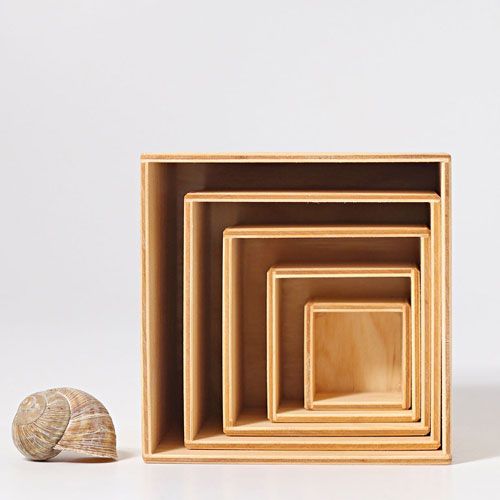 grimm's set van vier naturel houten nestkubussen met een slakkenhuis ernaast voor schaal.