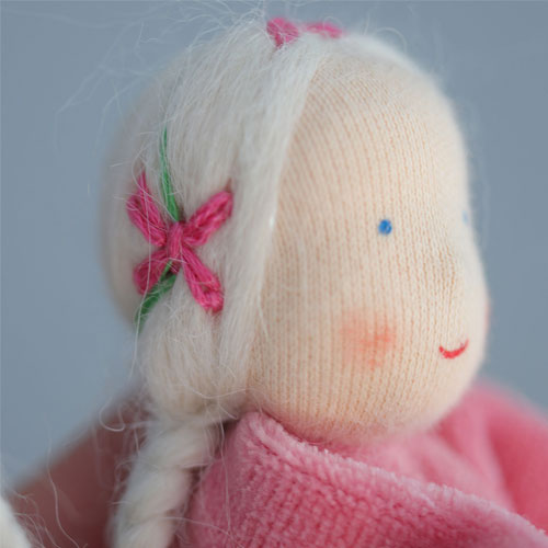 Zijaanzicht van het hoofd van de grimm's roze lavendelpopje handpop met een geborduurde roze bloem.