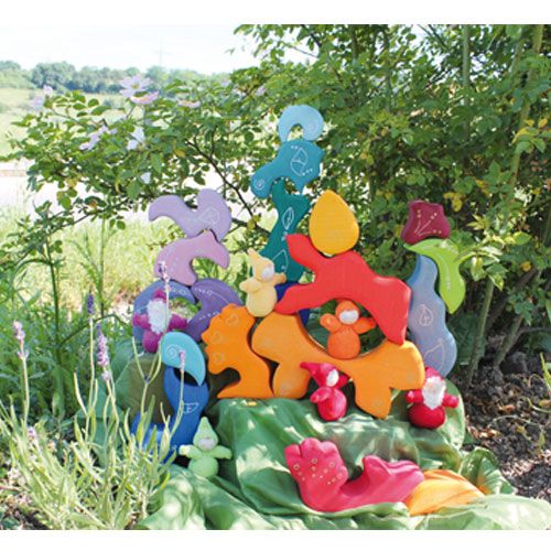 Collectie Grimm's houten stapelspeelgoed en figuren in een tuin.