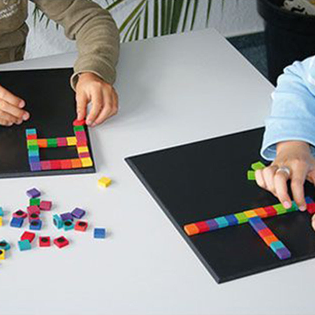 Twee kinderen spelen met kleurrijke magnetische blokjes op zwarte magneetborden.