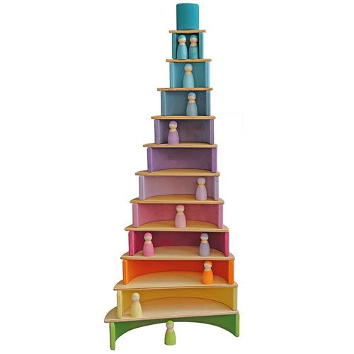 Een hoge grimm's stapeltoren van houten regenboogbogen en blokken met pastelkleurige popjes op elke verdieping.