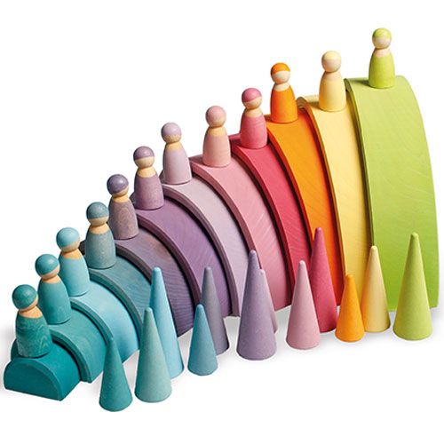 Een grimm's houten regenboog met pastelkleurige popjes en kegels, gerangschikt in een boog.