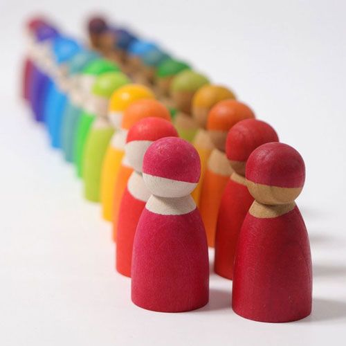 Een lange rij grimm's houten peg dolls in regenboogkleuren, van rood vooraan tot paars achteraan.