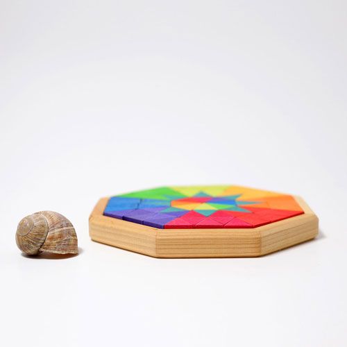 Grimm's houten puzzel in een achthoekige bak, met veelkleurige stukjes, naast een slakkenhuis voor schaal.